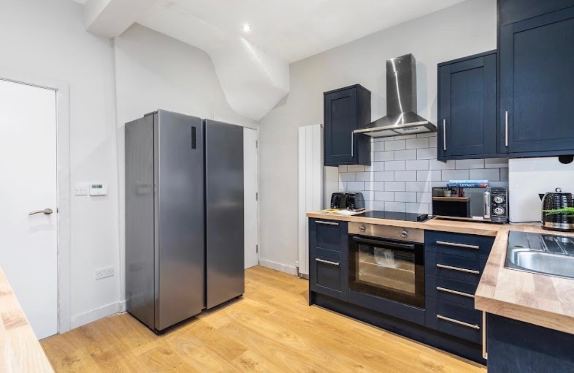 Modern BTL kitchen completed by HHB Contractors in Liverpool, featuring navy shaker cabinets, wooden worktops and vinyl flooring