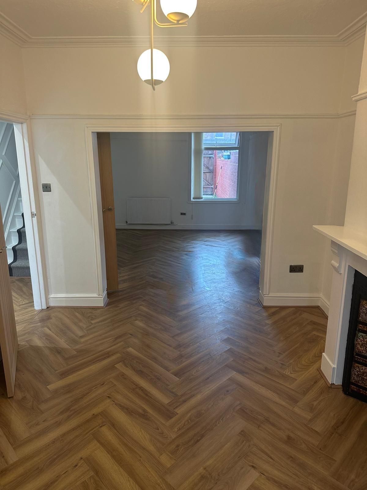 Dining room with herringbone flooring, globe pendant light and view through to the lounge