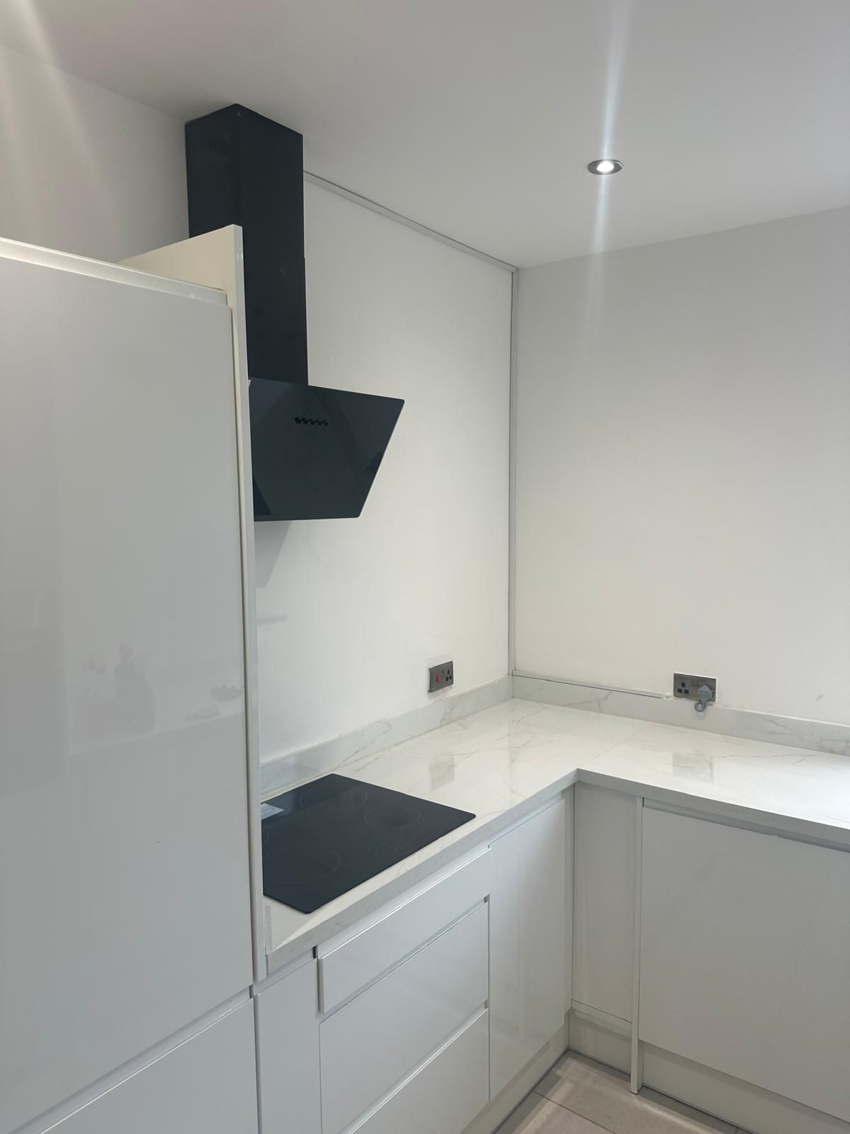 White gloss handleless kitchen with induction hob and angled black extractor