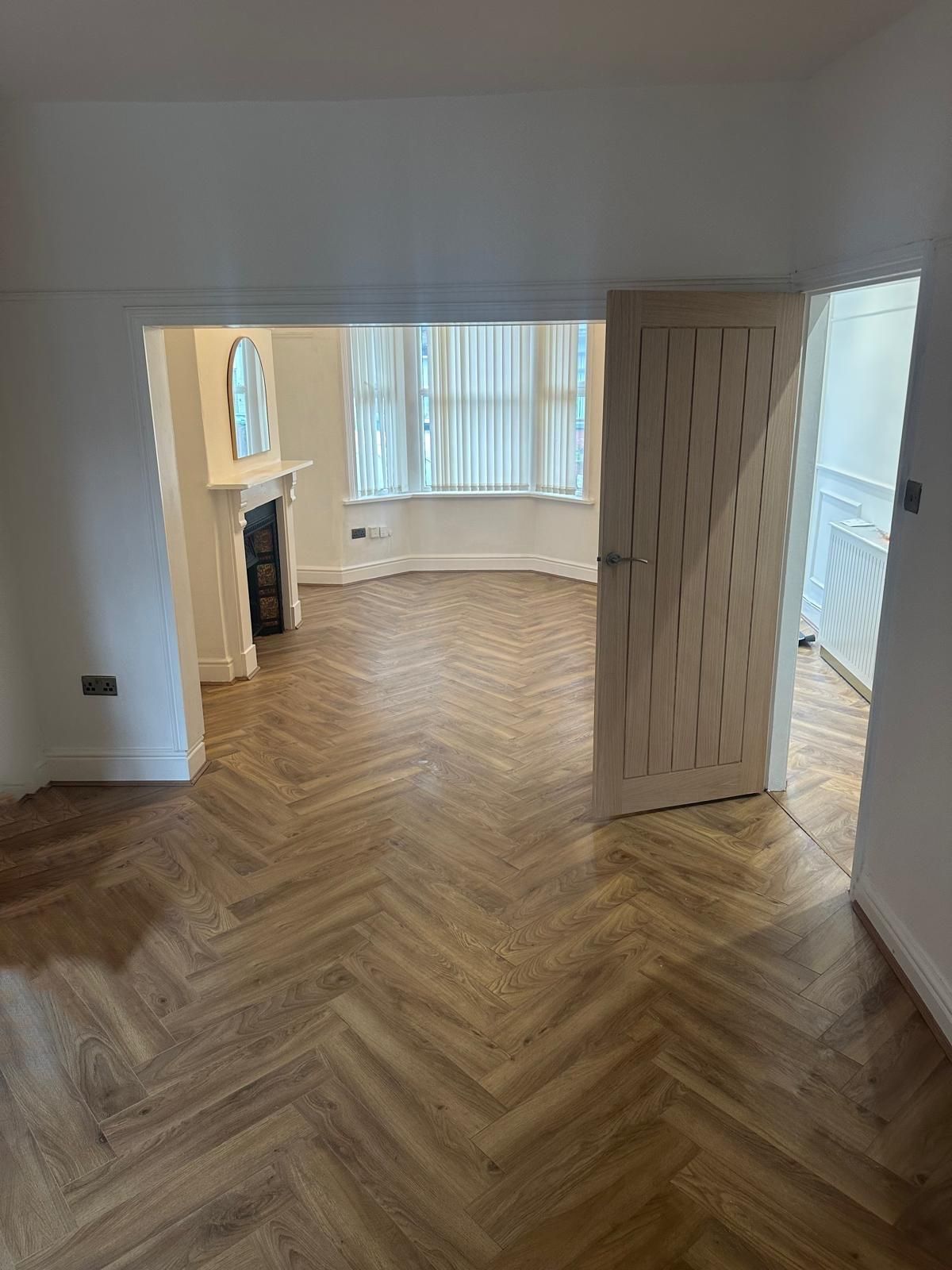 Through lounge with new herringbone flooring, oak door and restored fireplace