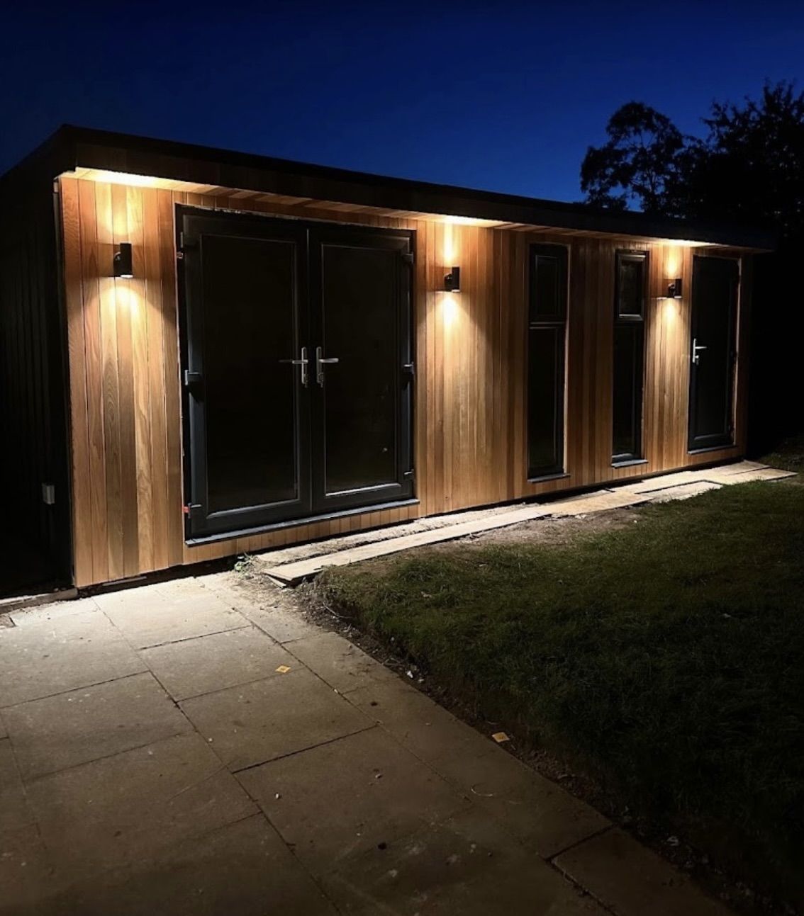 Garden room lit at night with external wall lights